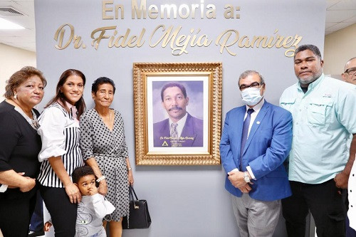 Familares del Dr. Mejía posan frente a su imagen.